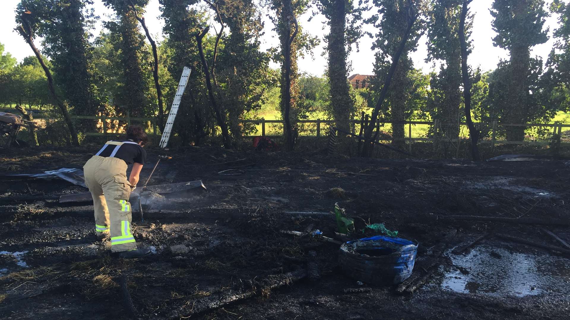 Sifting through the remains of a hay store and stables after the fire at the Modha's smallholding in Woodchurch