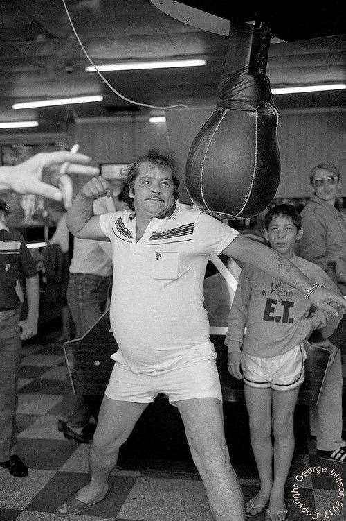 With cigarette in hand, this man takes aim at the punch machine. Copyright: George Wilson