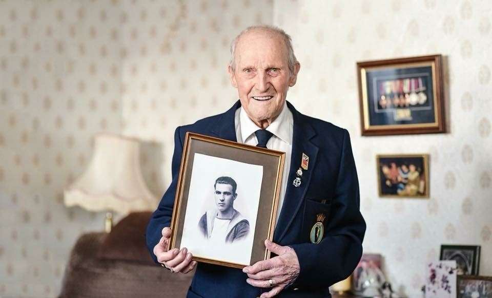 Mr Hollands holding a picture of himself in his 20s