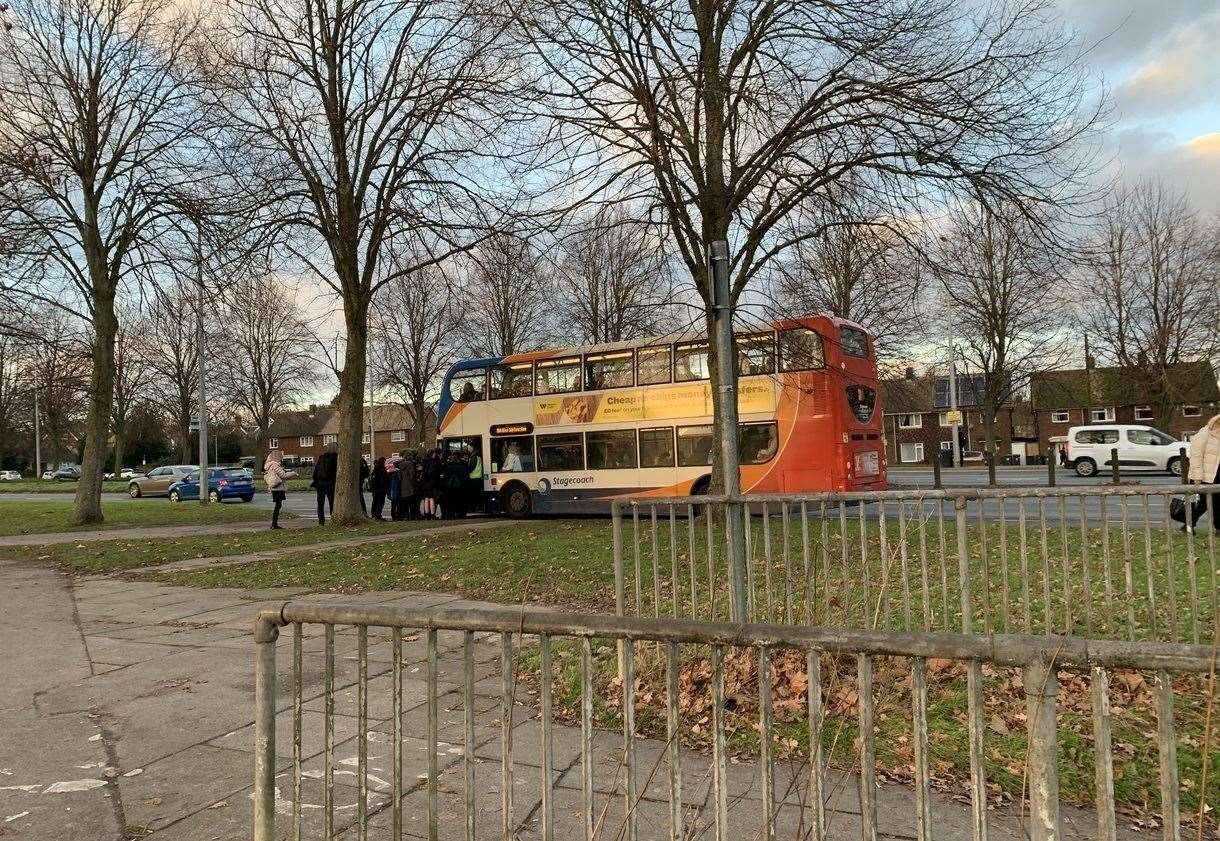 Pupils crowding around the bus stop in Rheims Way as a teacher from Canterbury Academy helps