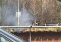 Fire on grass bank beside retail park