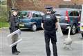 Police with riot shields guard injured swan