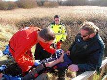 Medics inspect Mark Pamplin’s ankle which he fractured after slipping on mud