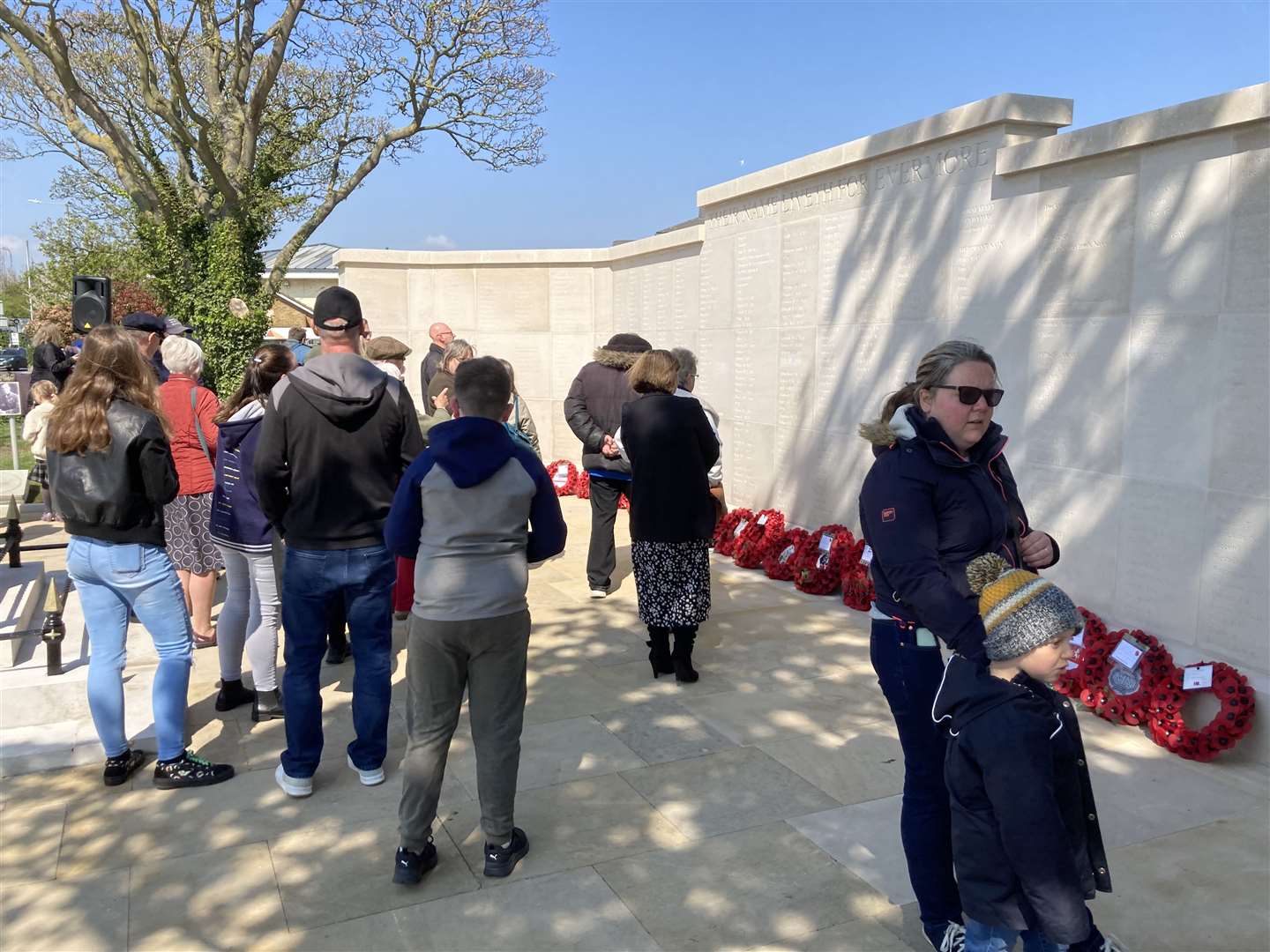 People inspect the names after the dedication of the new memorial wall in Sheerness