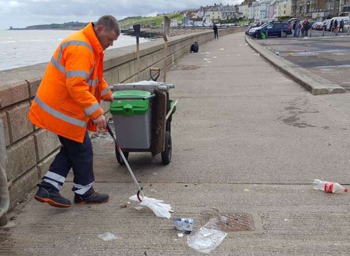 A Serco worker clears up after caravans leave car park