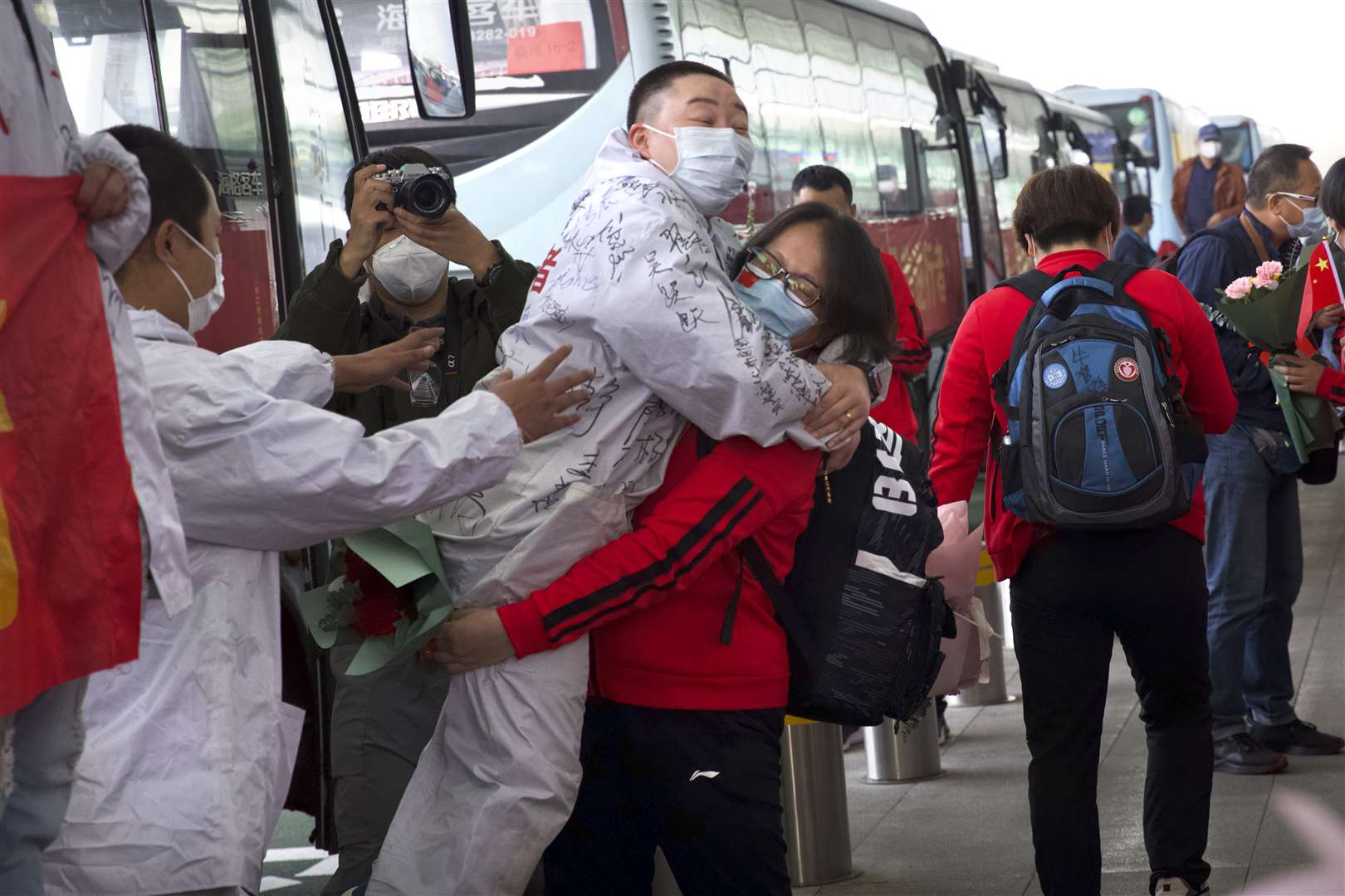 A medical worker from China’s Jilin Province, in red, embraces a colleague from Wuhan as she prepares to return home at Wuhan Tianhe International Airport (Ng Han Guan/AP)