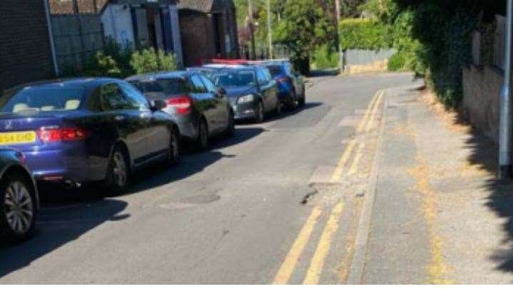 Parked vehicles reducing Gibraltar Lane, which leads to Castle Dene, to a single carriageway