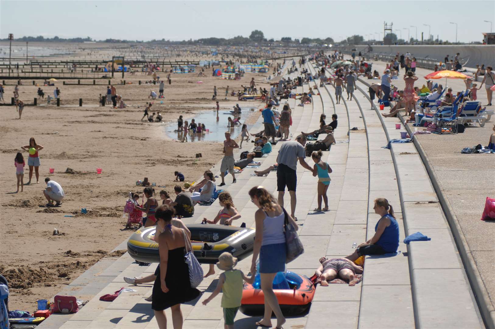 Sun seekers enjoy the new look sea wall and steps running the length of Dymchuch Beach Picture: Gary Browne (7551341)