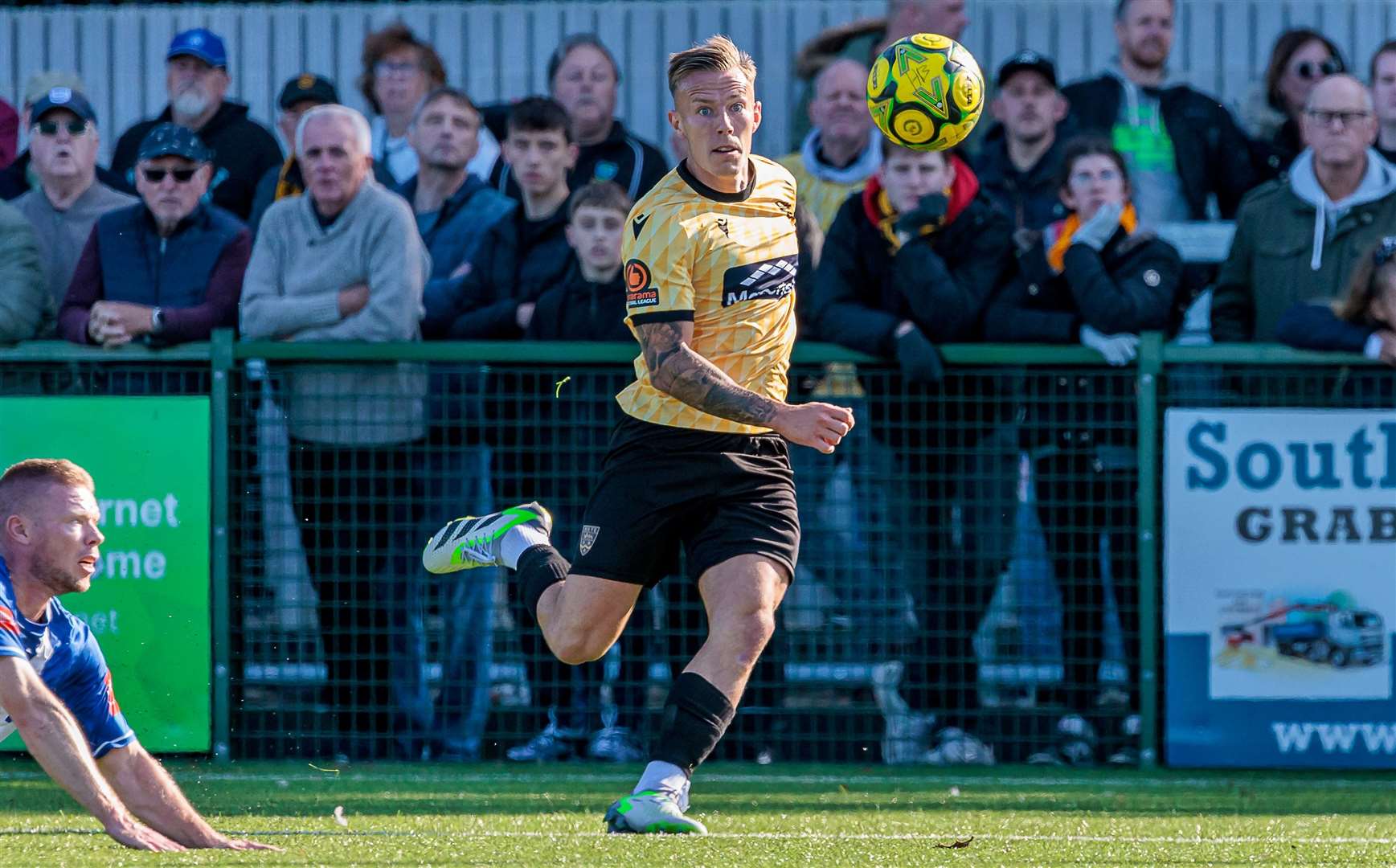 Maidstone skipper Sam Corne moves forward with Herne Bay midfielder Scott Heard on the deck. Picture: Helen Cooper