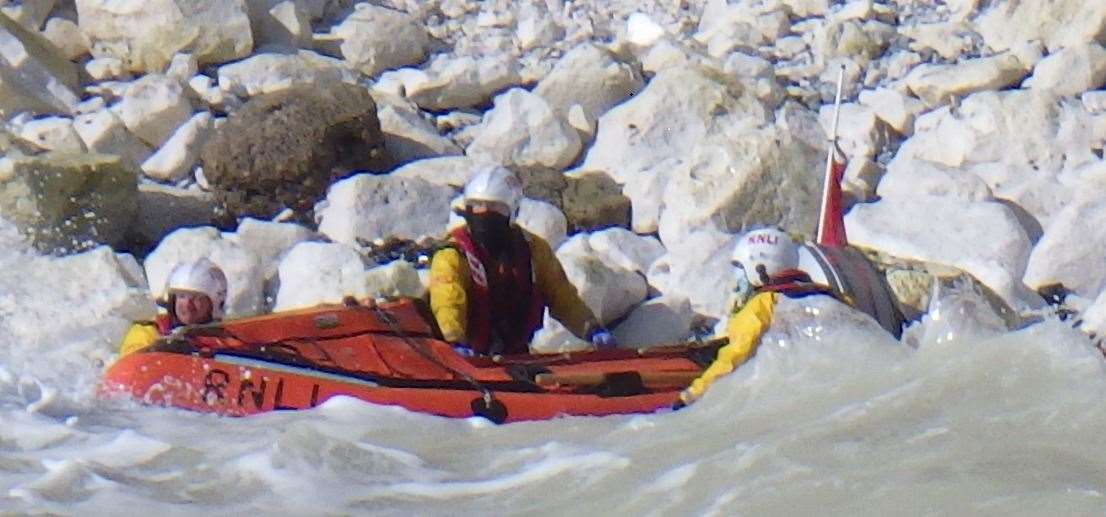 Crewmen go into the frothy sea to keep the Duggie Rodbard from the rocks. Picture: Walmer RNLI