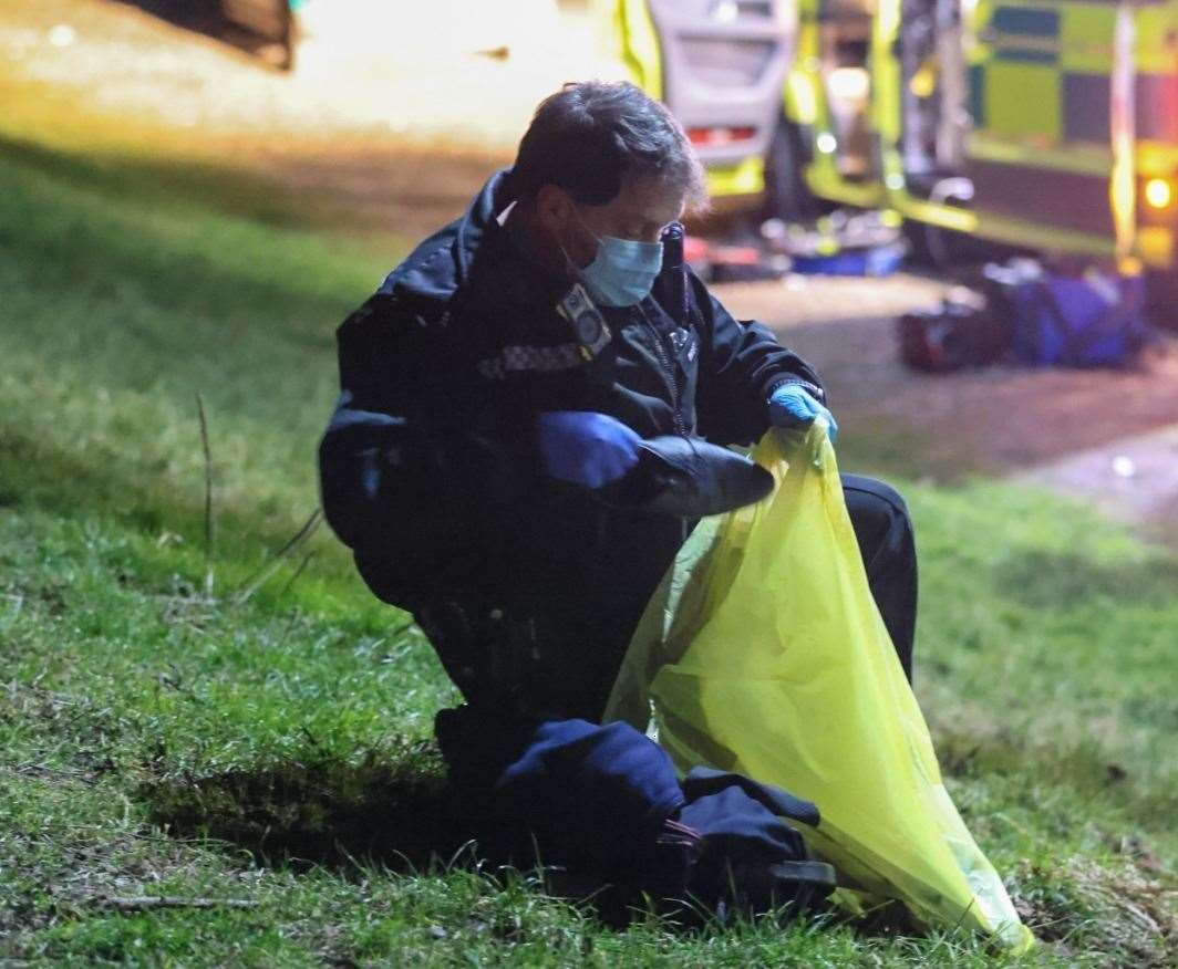 Police putting items of clothing in a bag in Mote Park