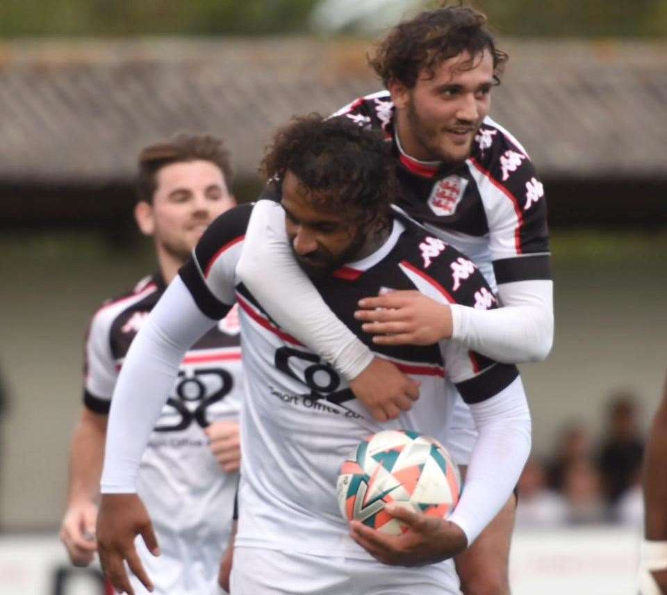 Stefan Payne is jumped on by new Faversham team-mate England Kurti as he completes his hat-trick in Saturday’s 3-1 win over Punjab United. Picture: Ian Scammell