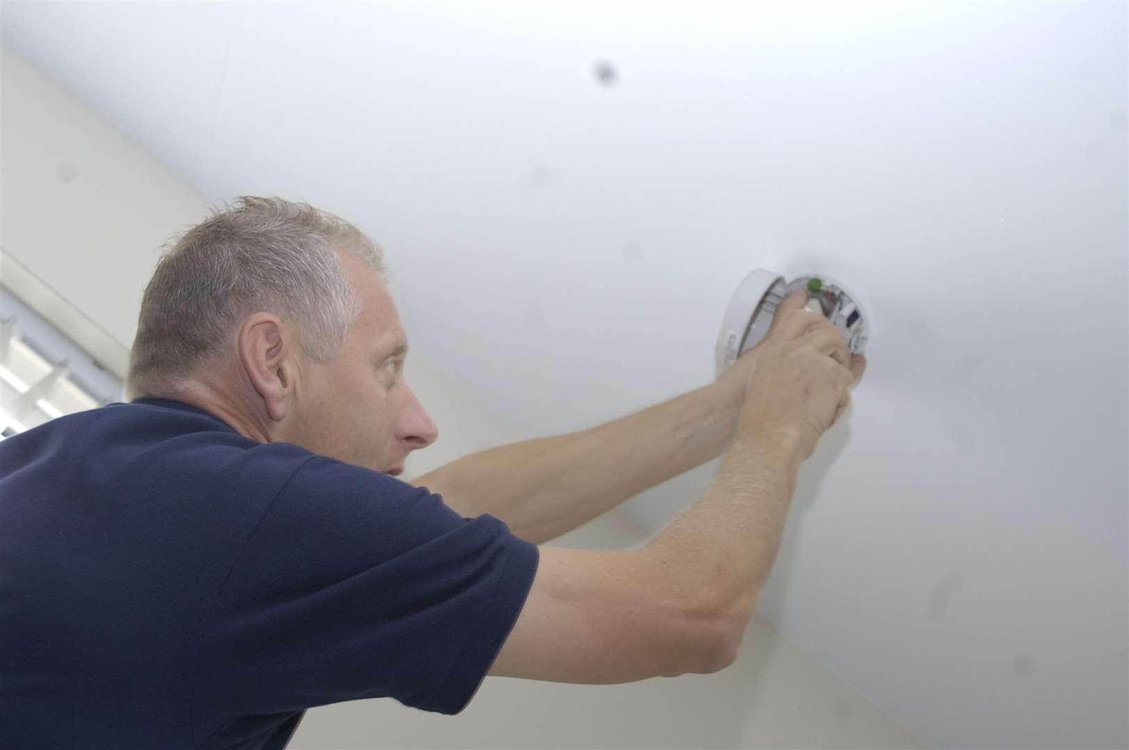 A technician fits a fire alarm as part of the community fire prevention scheme. Library picture