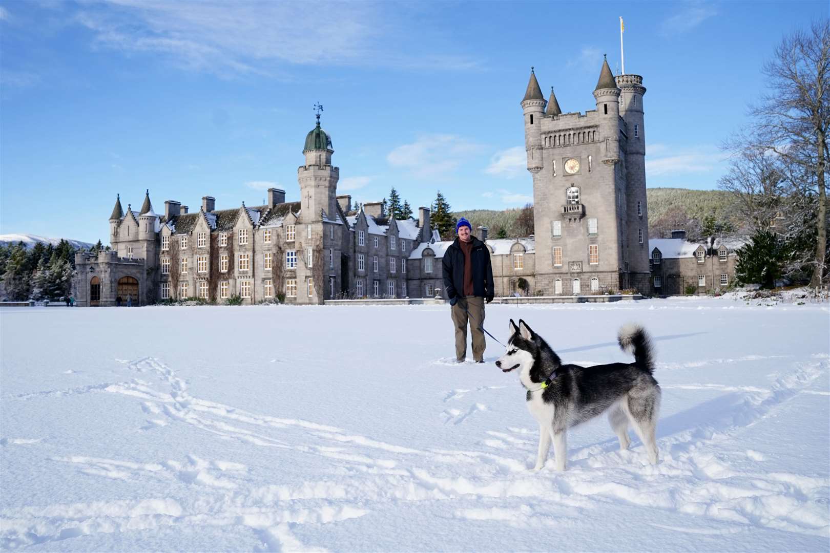 Ryan Phillips walks Arty the Siberian husky in the snowy grounds of Balmoral (Jane Barlow/PA)