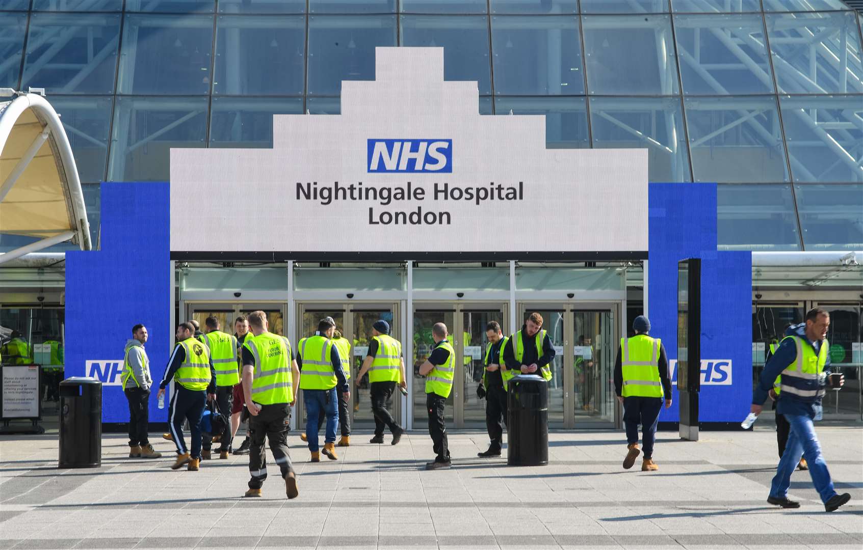 Workers outside entrance of the ExCel centre in London which is being made into a temporary hospital – the NHS Nightingale hospital, comprising of two wards, each of 2,000 people, to help tackle coronavirus (PA)