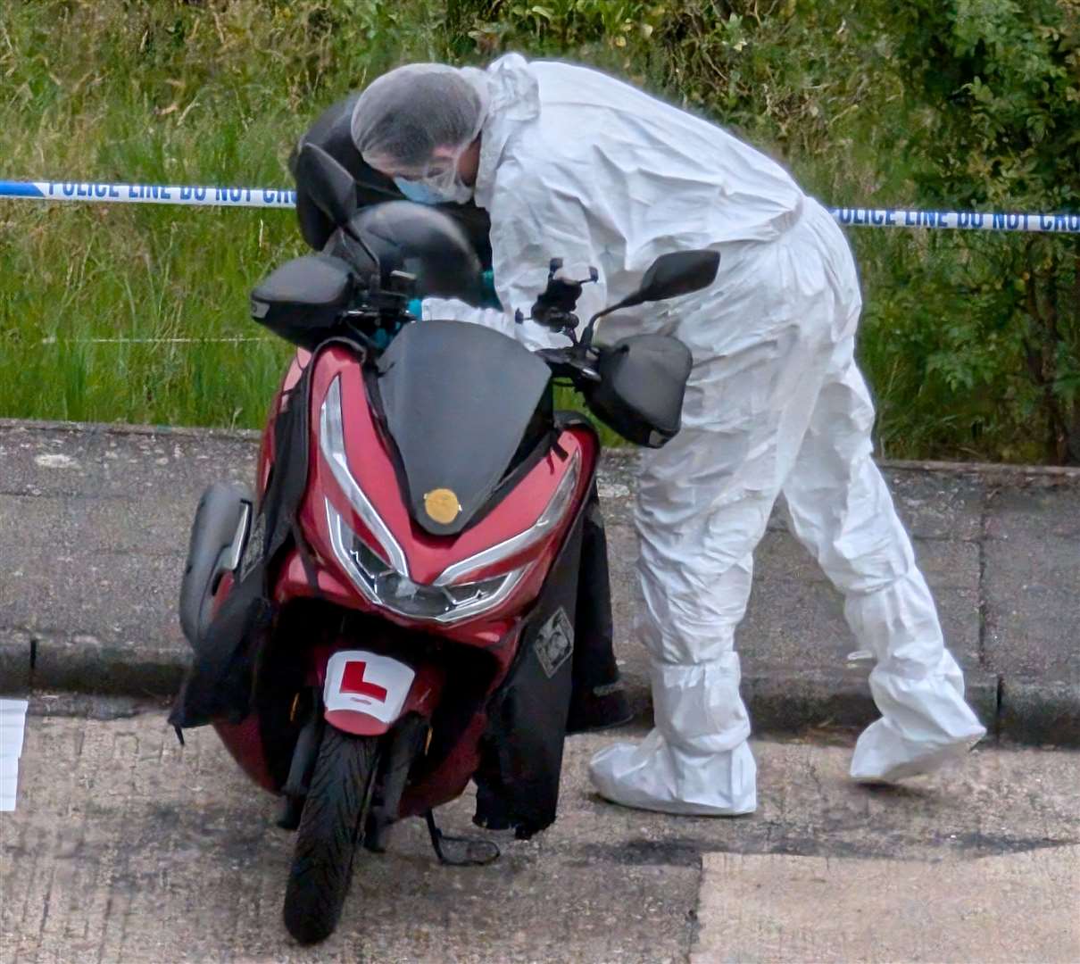 A forensic officer looking at a moped in Mooring Road, Rochester after a soldier was attacked in Sally Port Gardens, near Brompton Barracks