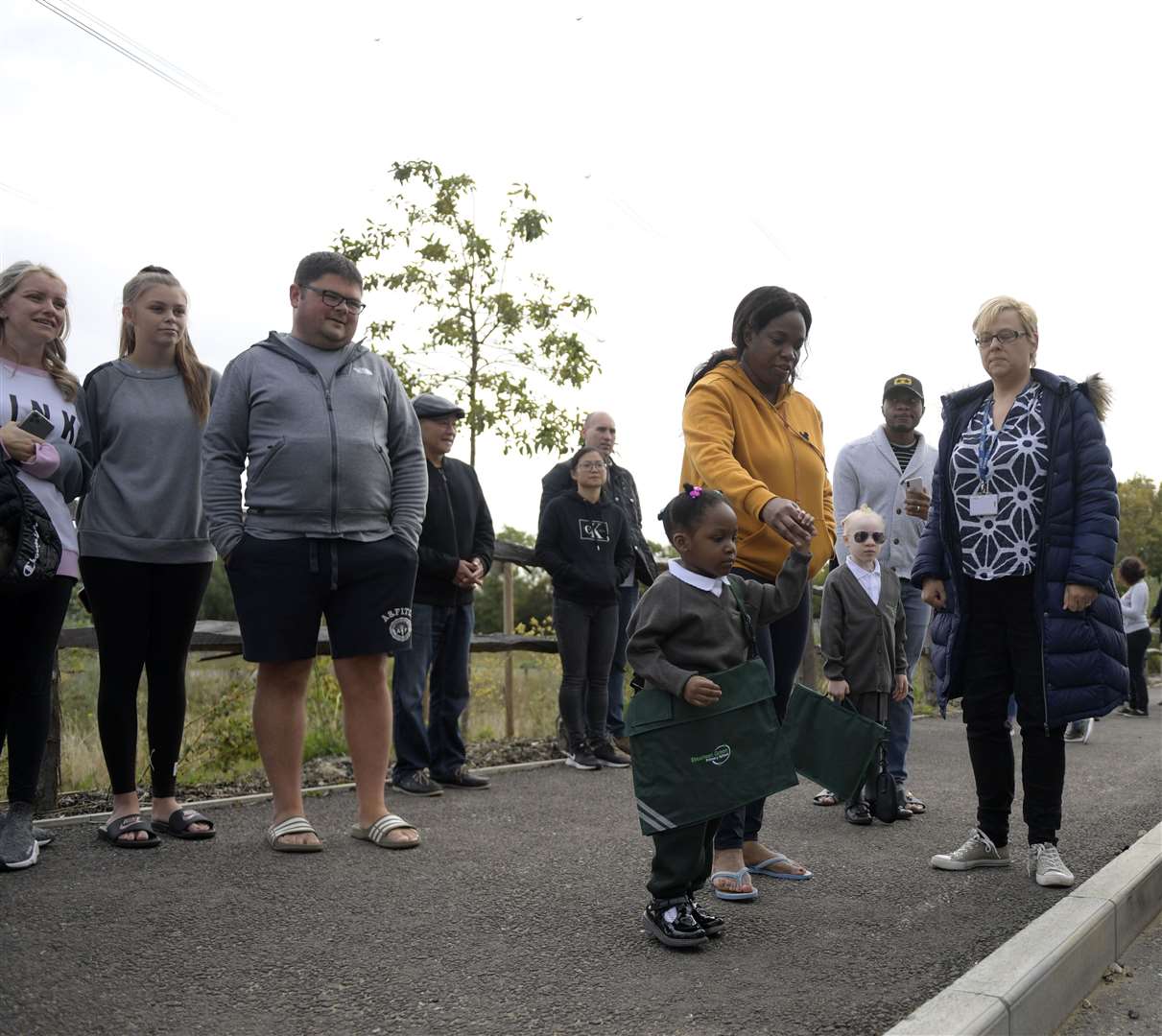 Parents see off their children on to the bus at the new but not yet ready Ebbsfleet Green Primary School