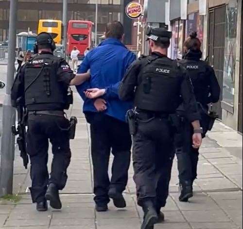 A man is led away from the scene in handcuffs. Pic: Mason Cran