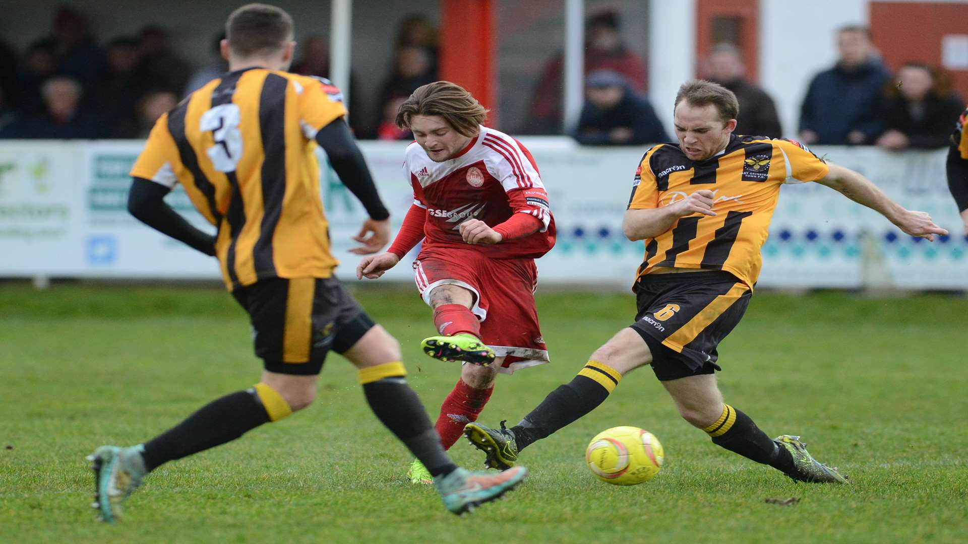 Hythe's Alfie May gets a shot away despite the attention of two East Grinstead defenders Picture: Gary Browne