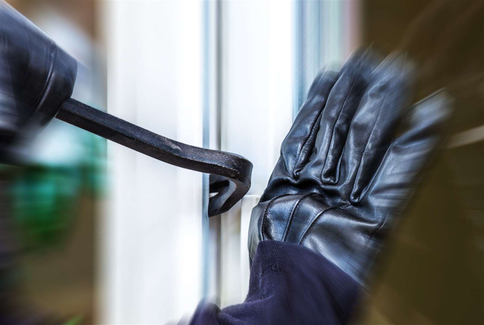 A burglar opens a window with a crowbar. Stock picture