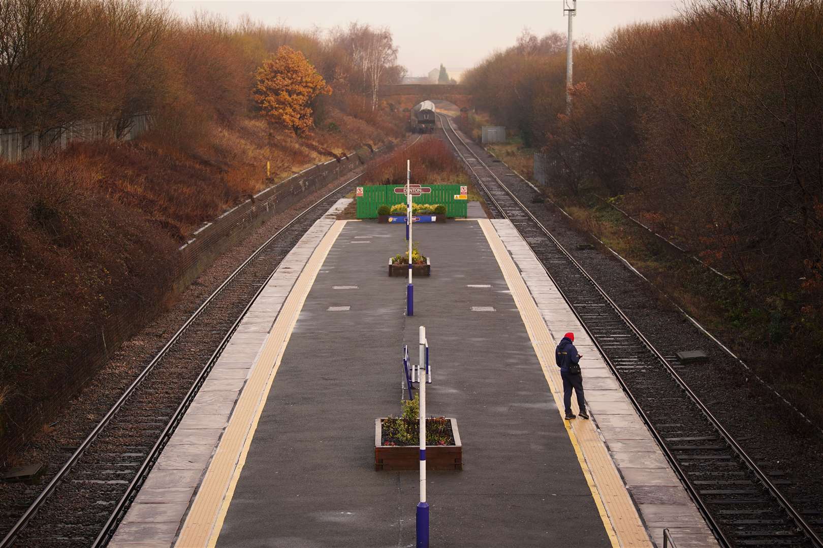 A passenger waits for a train at Denton railway station in Greater Manchester (PA)