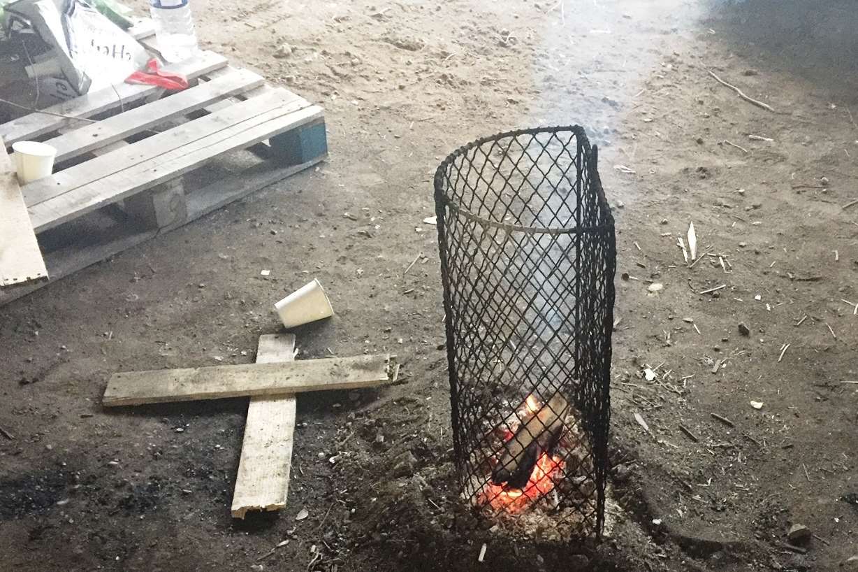 The group keep warm by a small camp fire