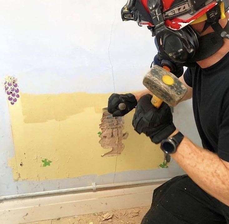 A firefighter makes a hole in the wall as he attempts to rescue Ollie the cat in Broadstairs. Picture: Instagram/KFRS