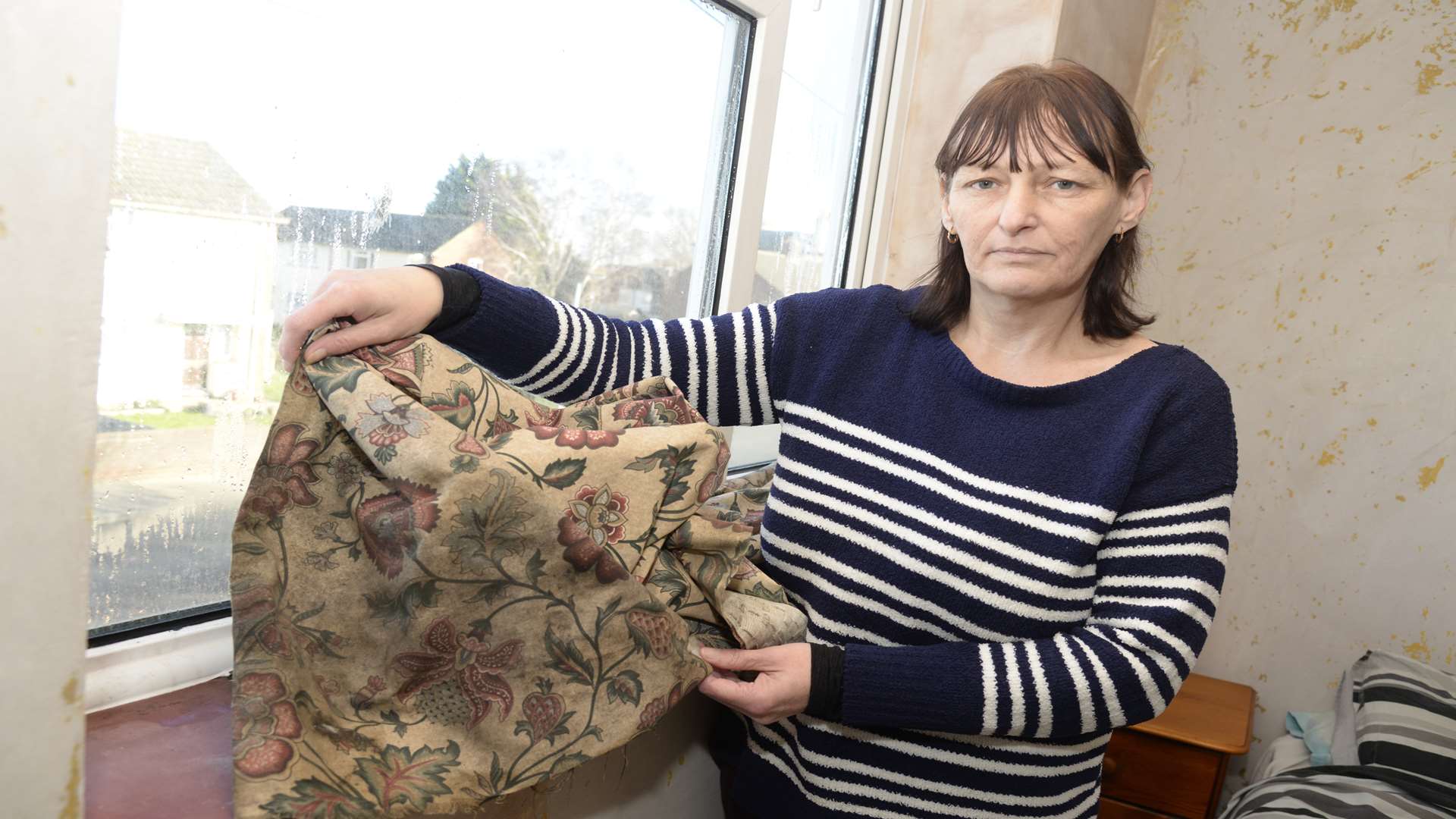 Hayley Flanagan with curtains which have had to be replaced because of continuous damp problem.