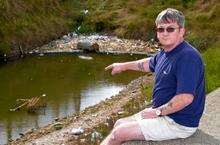 Steven Askew points out the rubbish that has accumulated in the water between the sea wall and the old dockyard walls