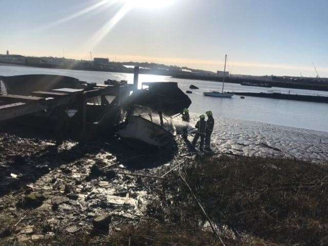 Firefighters damp down the damaged boat on River Medway off Canal Road, Strood