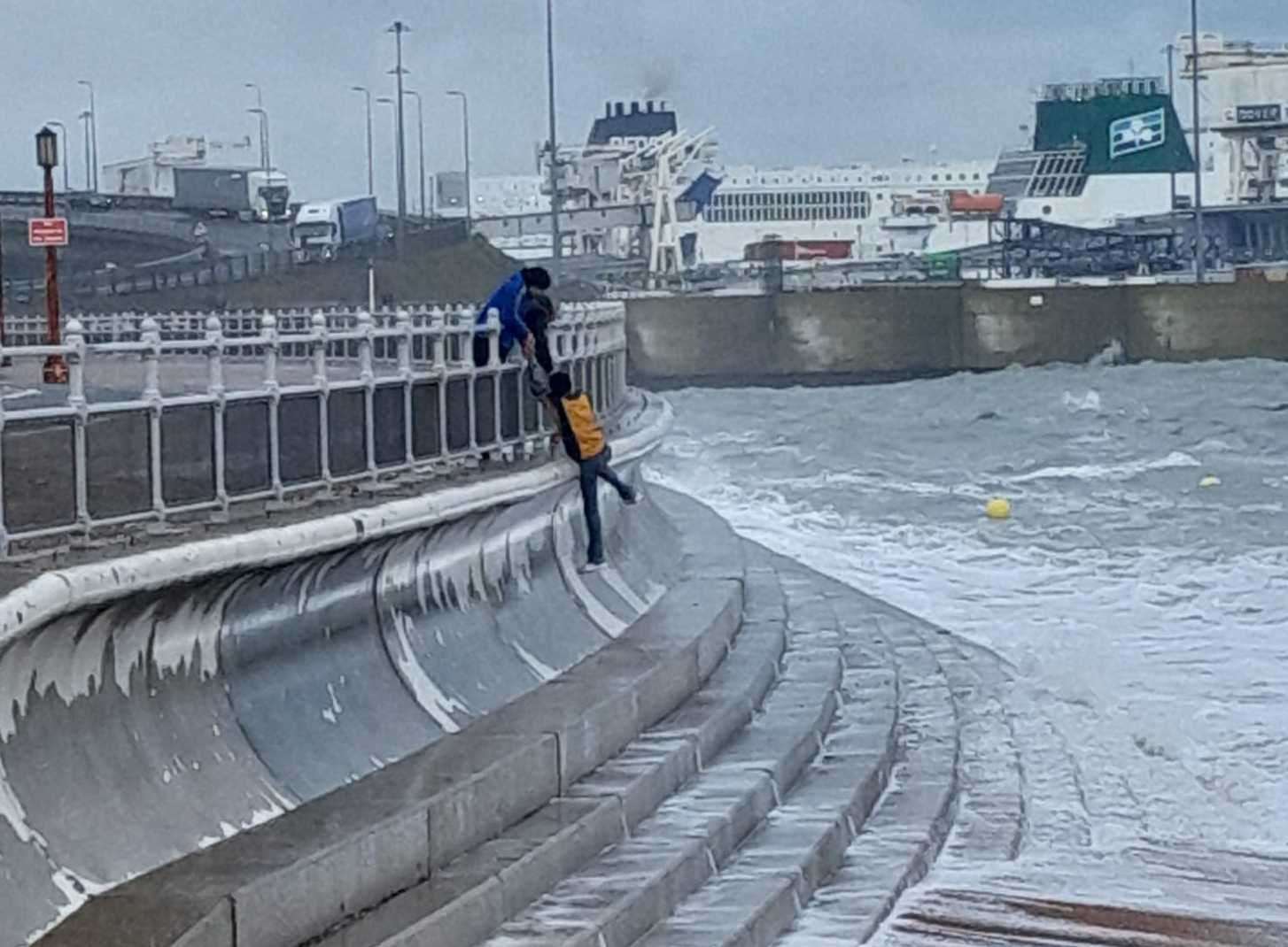 John Bain being pulled to safety by his son and friend after being slammed against a sea wall in Dover