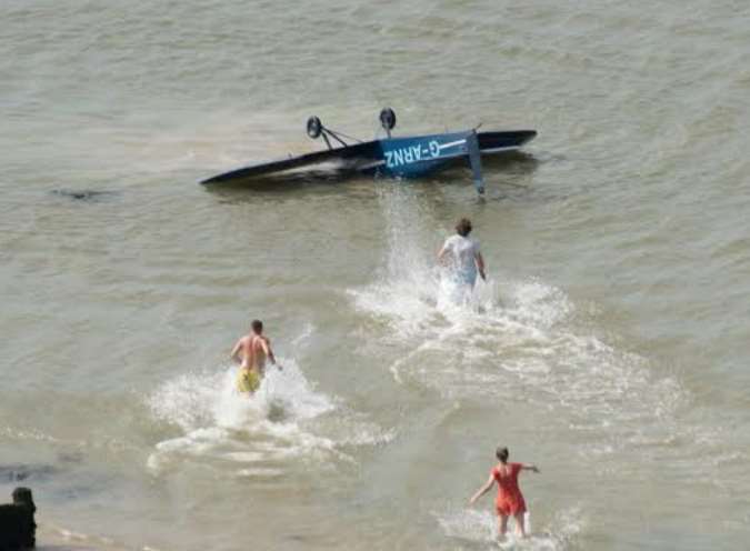 Onlookers - including Michael Cox in the white t-shirt - rush to the pilot's aid. Pic by Nigel Hancock