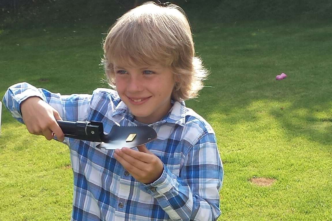 Xander displays his lucky find on the trowel he used to dig the holes