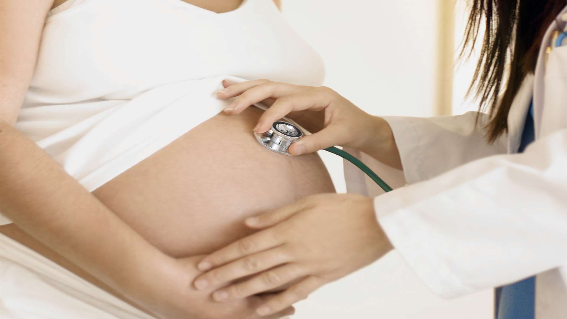 Midwife monitors baby's heartbeat. Stock image.