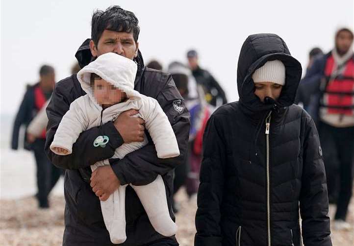 A group of people thought to be migrants, including young children, walk up the beach in Dungeness. Picture: Gareth Fuller