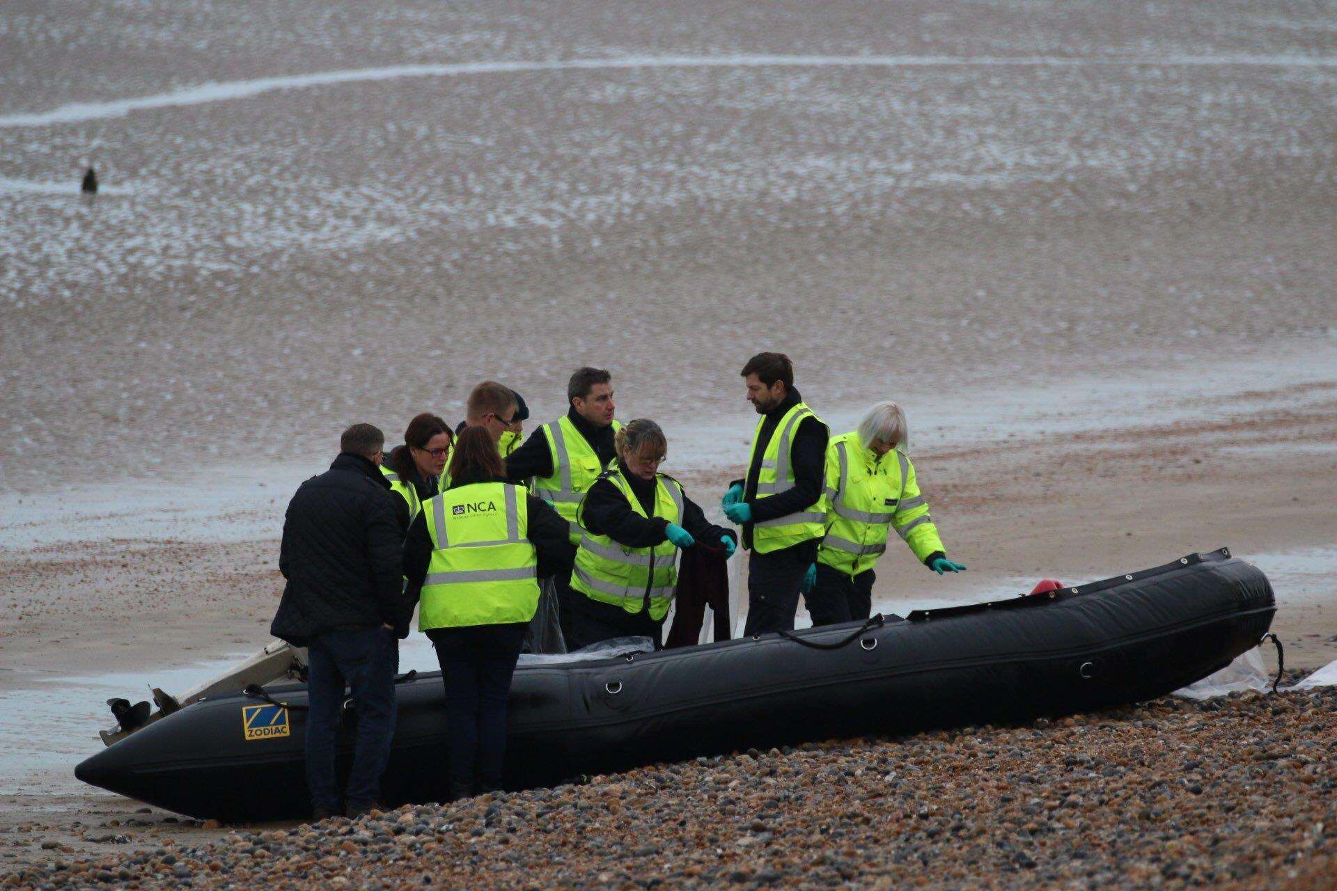 Officers wearing hi-vis National Crime Agency jackets examine a boat on the shore at Greatstone. Picture: Susan Pilcher