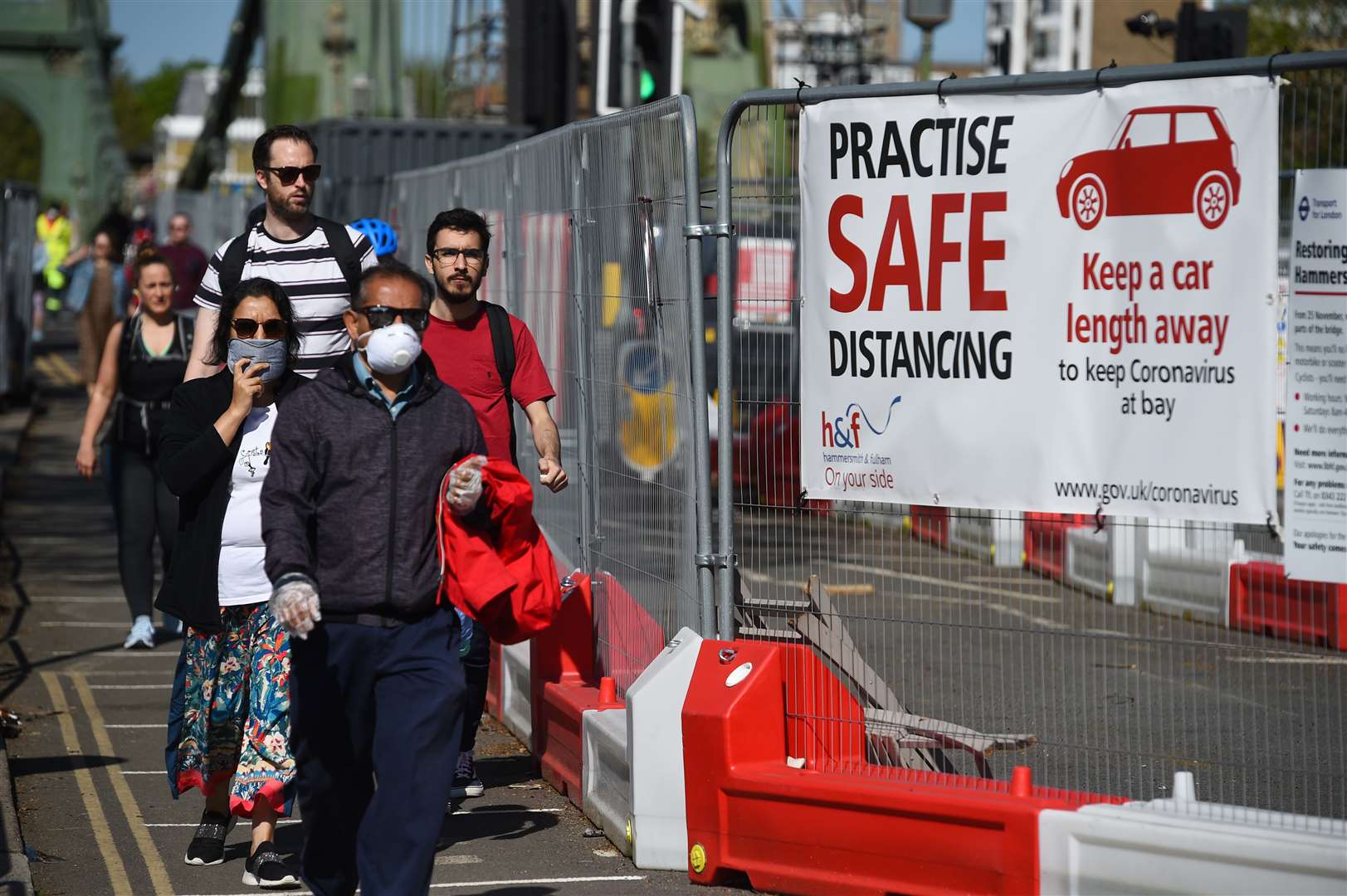 People observe social distancing as they cross Hammersmith Bridge in London (Kirsty O’Connor/PA)