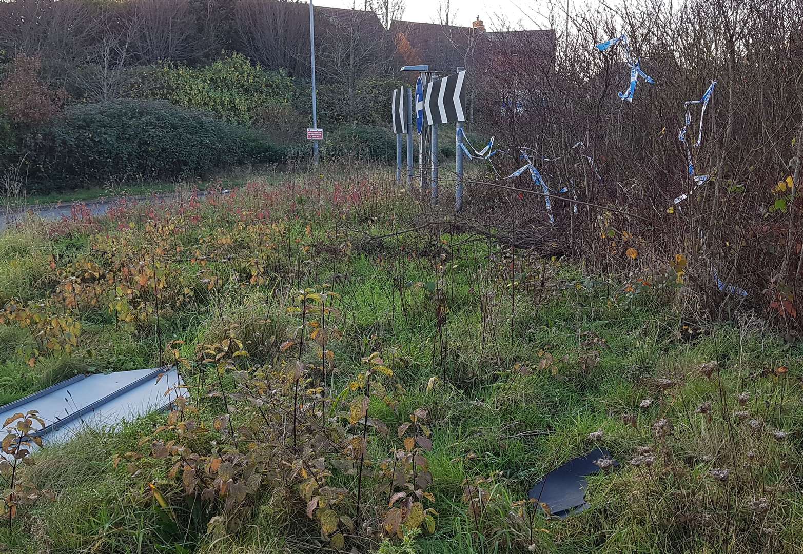 Police tape, a broken road sign and car parts remain