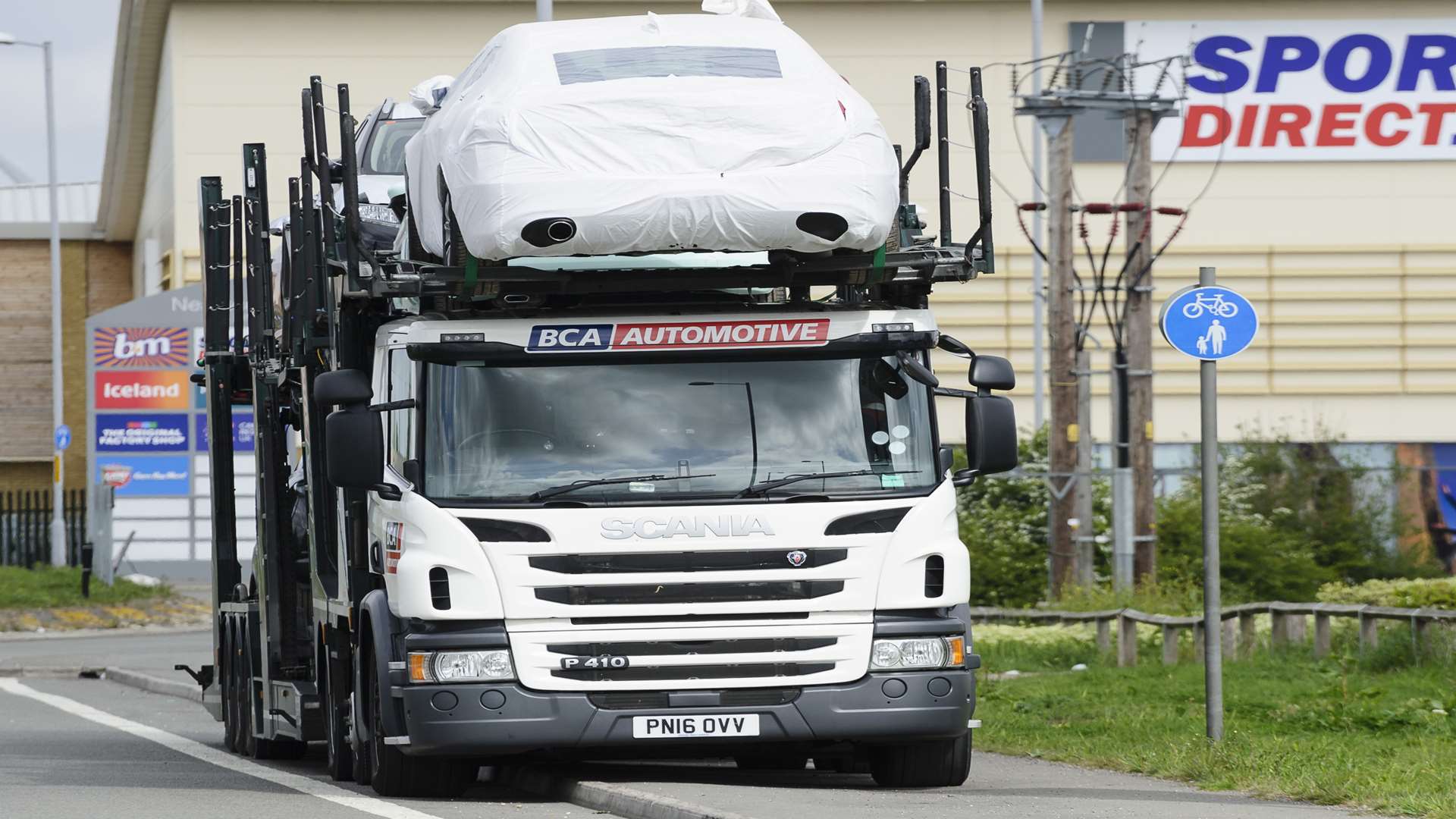 A car transporter, parked almost fully on the path in Thomsett Way.