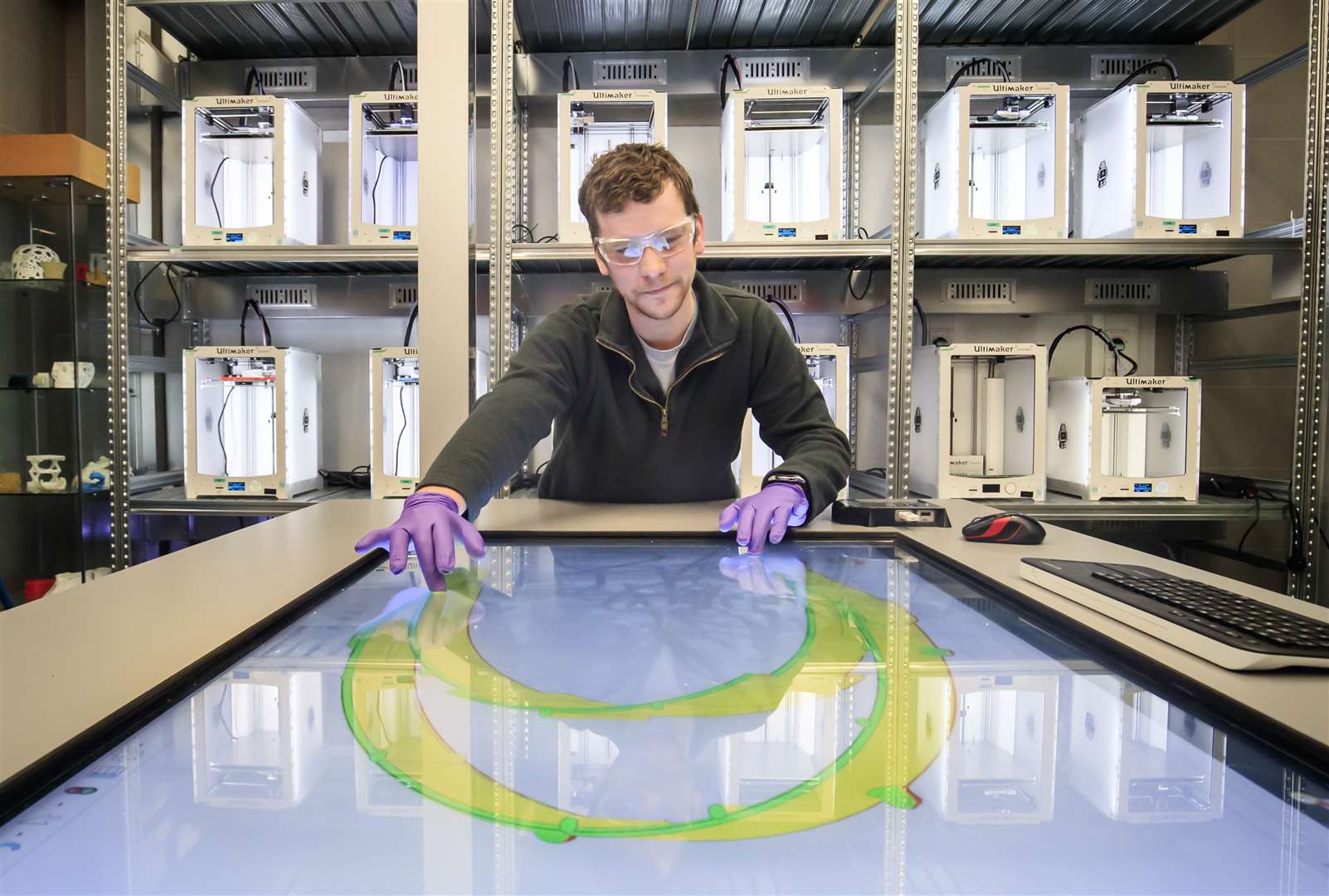 Brian Houston, lecturer at the University of Hull, looks at a design for a faceguard with a bank of 3D-printers behind him (Danny Lawson/PA)