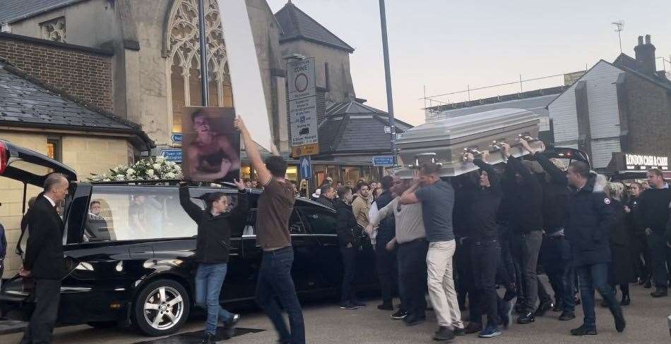 Pictures are held aloft of the victims of a crash which claimed four lives on October 10, near Headcorn