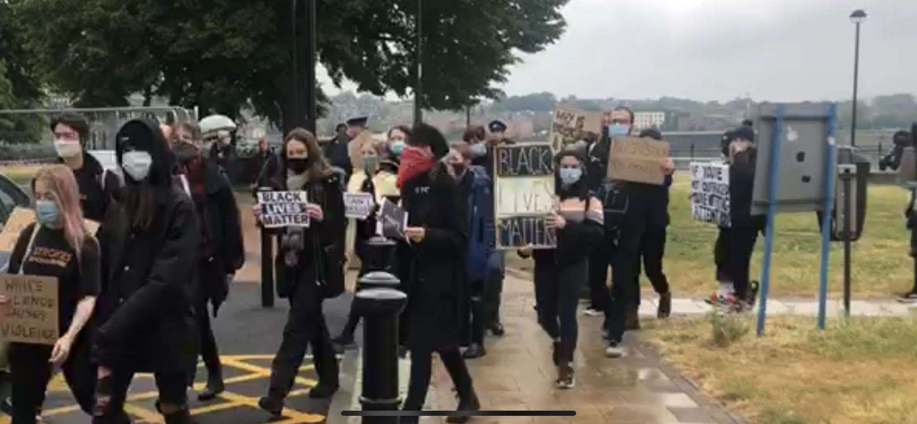 Hundreds of people are marching carrying placards and signs