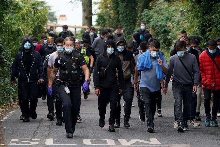 Police and Border Force officers escort a group of people from the beach at St Margaret's Bay. Picture: Gareth Fuller/PA