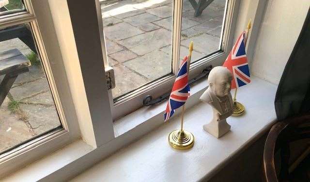 Supported on each side by a union flag, this small bust of Winston Churchill was placed alongside a photograph of The Queen