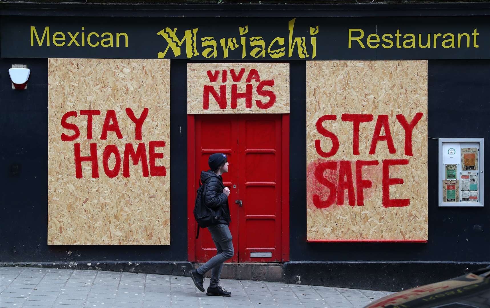 A person passes a boarded up restaurant in Edinburgh (Andrew Milligan/PA)