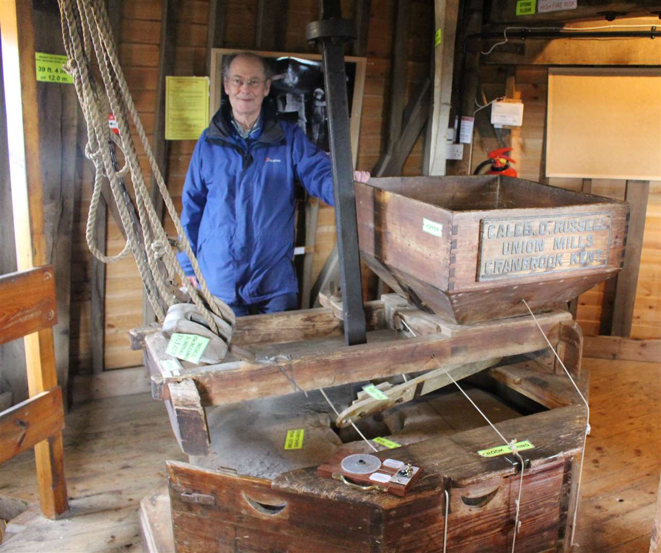 David Hall, a volunteer miller, beside a set of Derbyshire Peak millstones