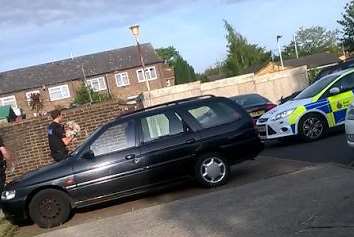 One of the dogs is carried away from the Kemsley property by a police officer