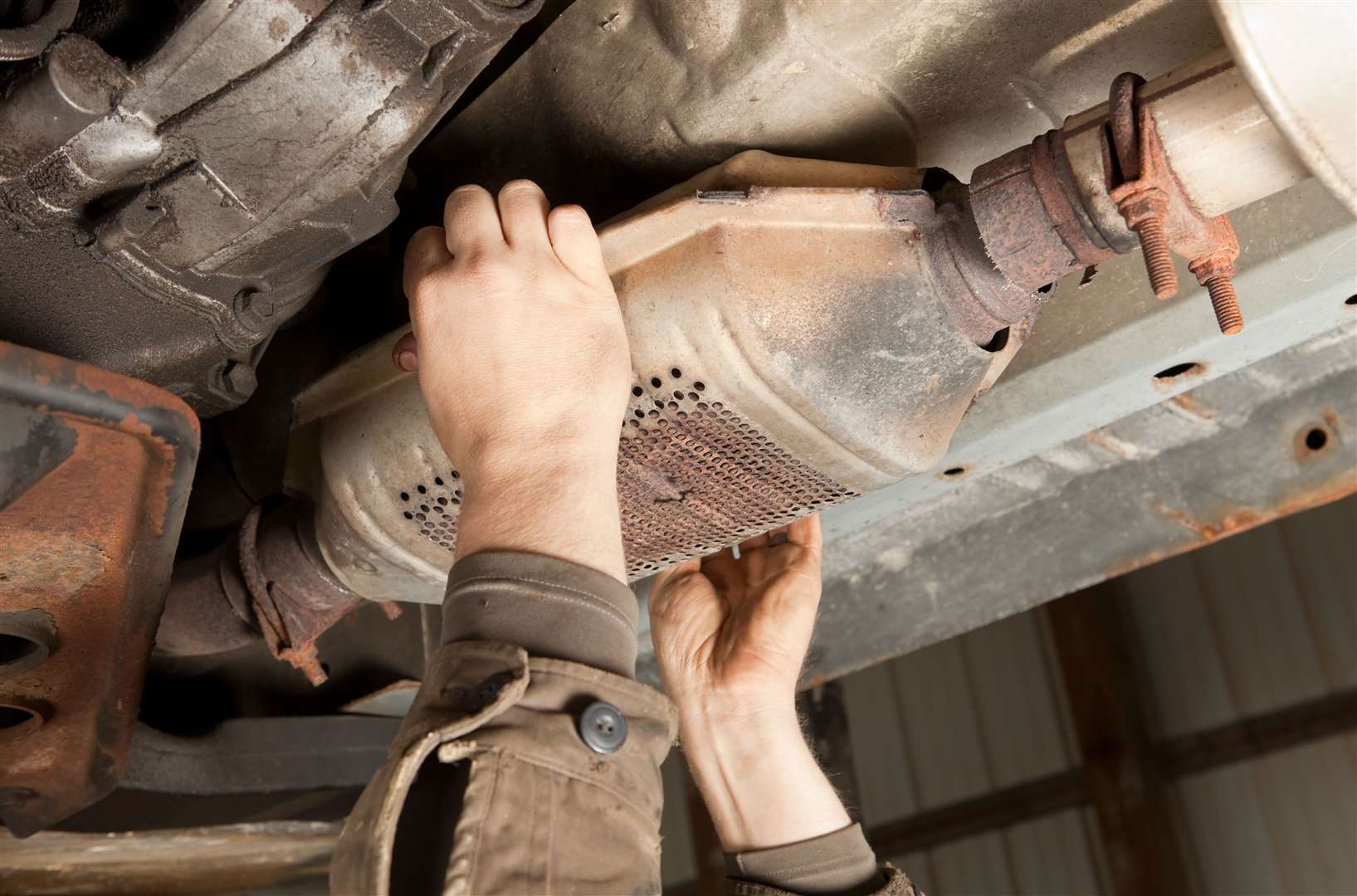 A catalytic converter is removed from under a car. Stock picture