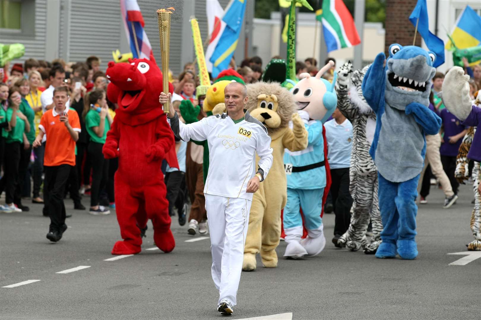 Torchbearer Kevin French in Ashford, followed by mascots