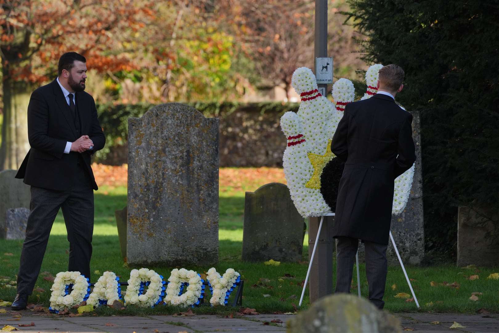 A funeral director places a floral tribute which said ‘Daddy’ in the churchyard at the funeral service (Jonathan Brady/PA)